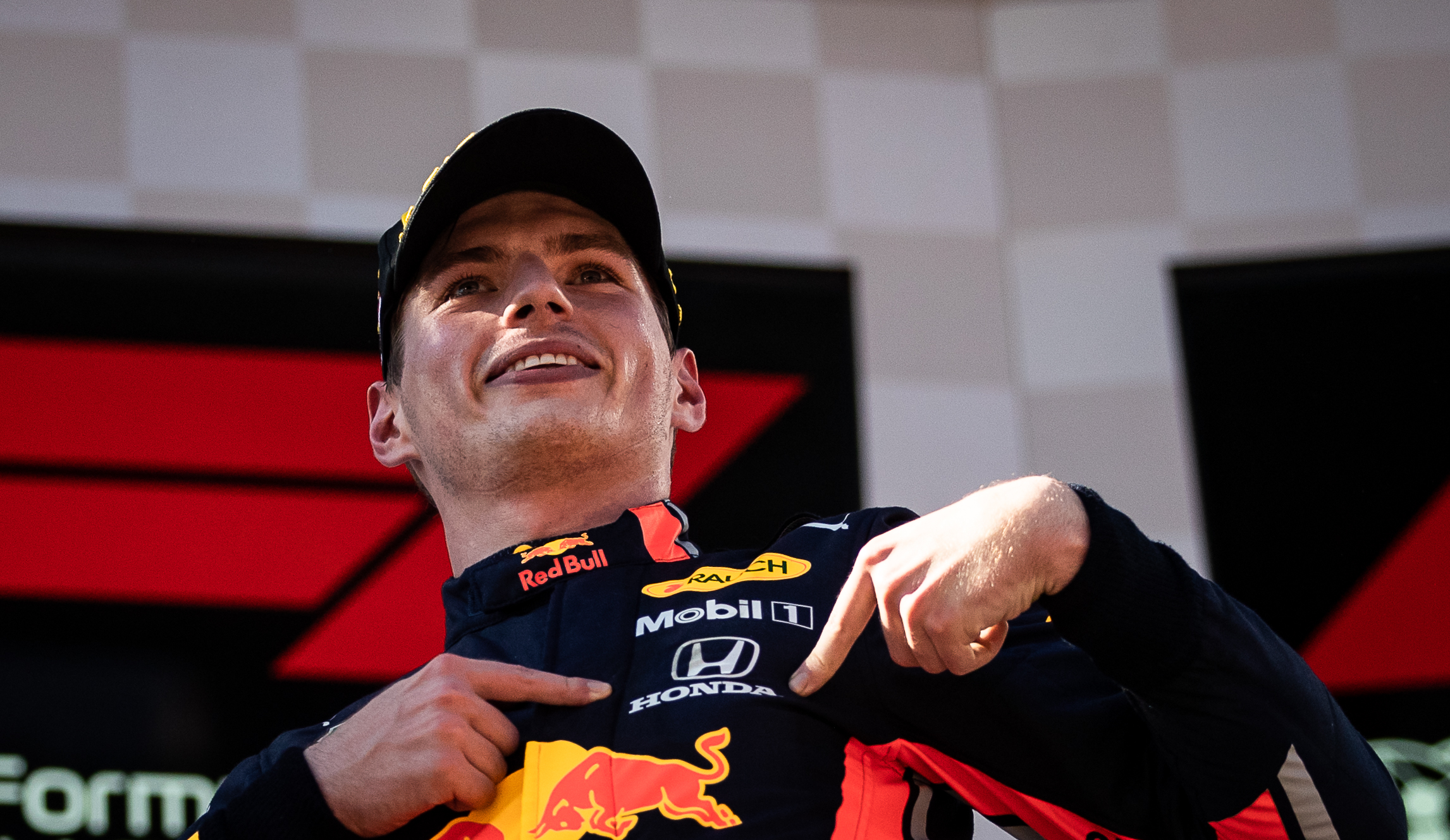 Max Verstappen wijst naar Honda-logo op Red Bull-pak